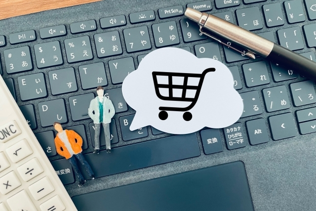 キーボードの上にある人形とショッピングカートの絵札