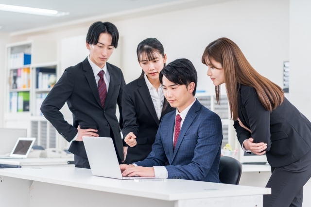 デスクトップを取り囲む会社員たち