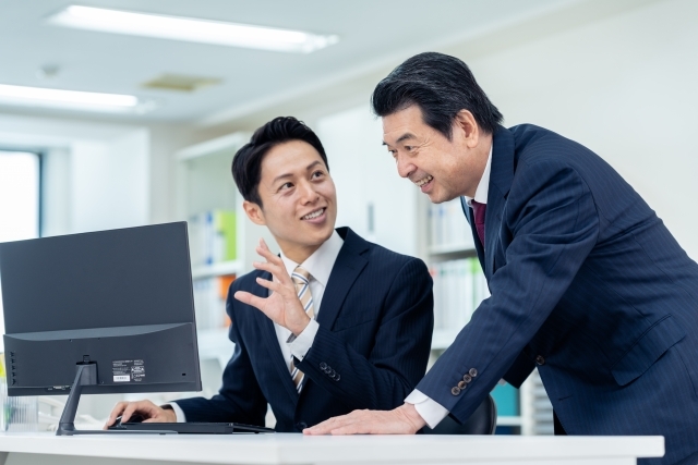 デスクトップを前に話し合う会社員