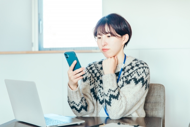 スマホを見ながら考え込む人