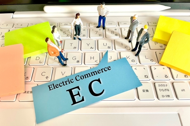 パソコンの上に置いてある人形とECと書かれた付箋