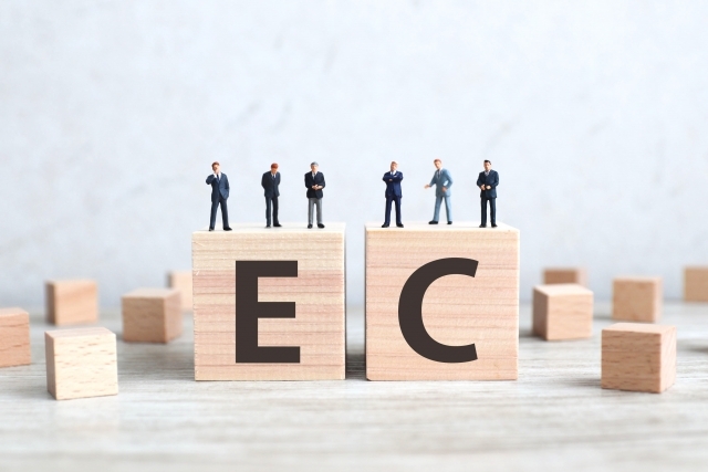 ECと書かれた木のブロックに乗っている人形